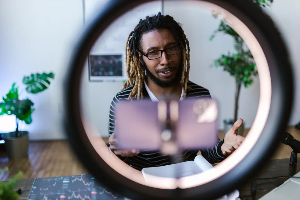 A creator speaking to a phone camera through a ring light in a home studio